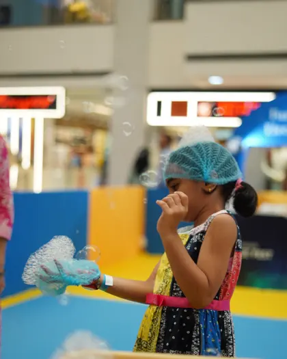 A girl catching a soap bubble on her gloved hand