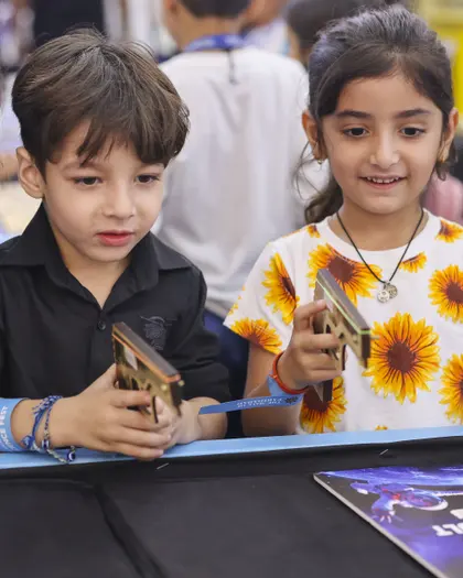 Two children examining the wooden model they have just built at a MakerMasti science table