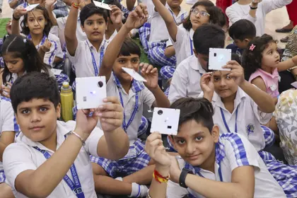 School children holding diffraction cards up to their eyes during a light and colour session