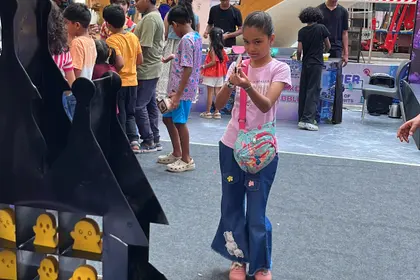 A girl taking aim at a target board with the rubber-band launcher she built