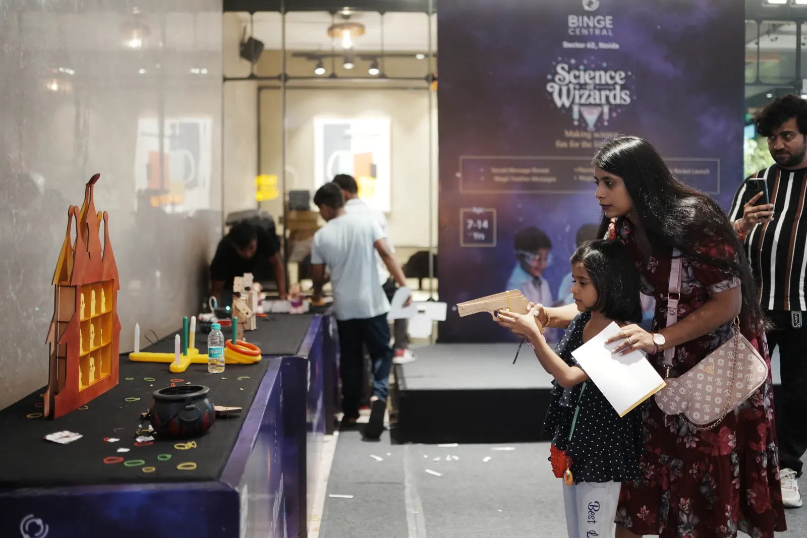 Children and parents gathered around the Science Wizards activity stand at Binge Central mall